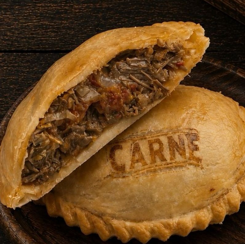 Empanada de carne partida al medio, mostrando el relleno de carne cortada a cuchillo.